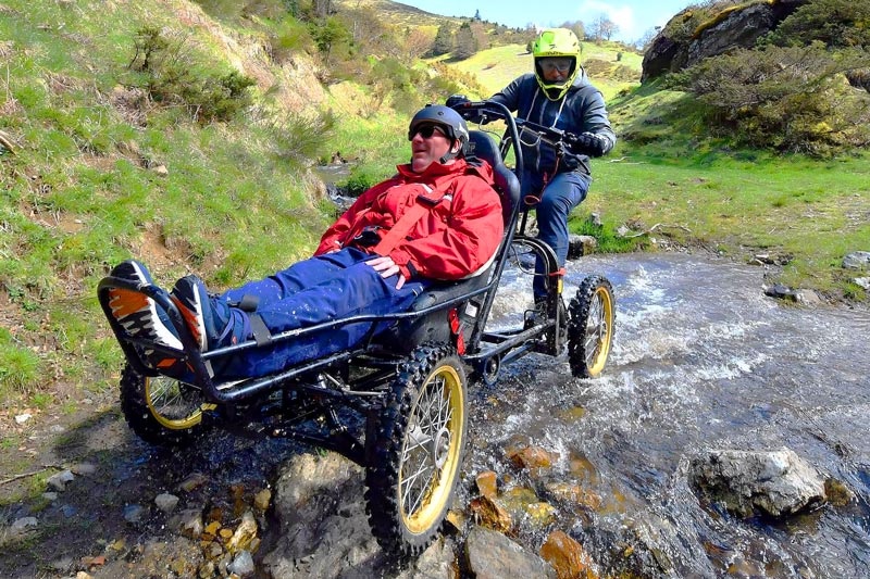 Fauteuil handicapé de descente piloté traversant une petite rivière Fauteuil handicapé de descente piloté traversant une petite rivière